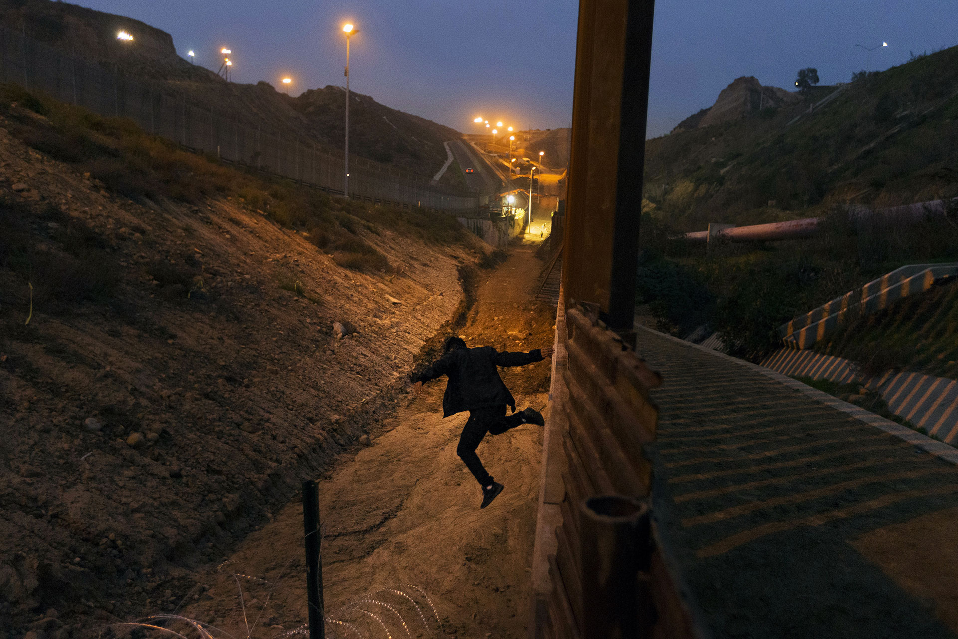 A Honduran migrant jumps from the U.S. border fence in Tijuana, Mexico on 21 December 2018.