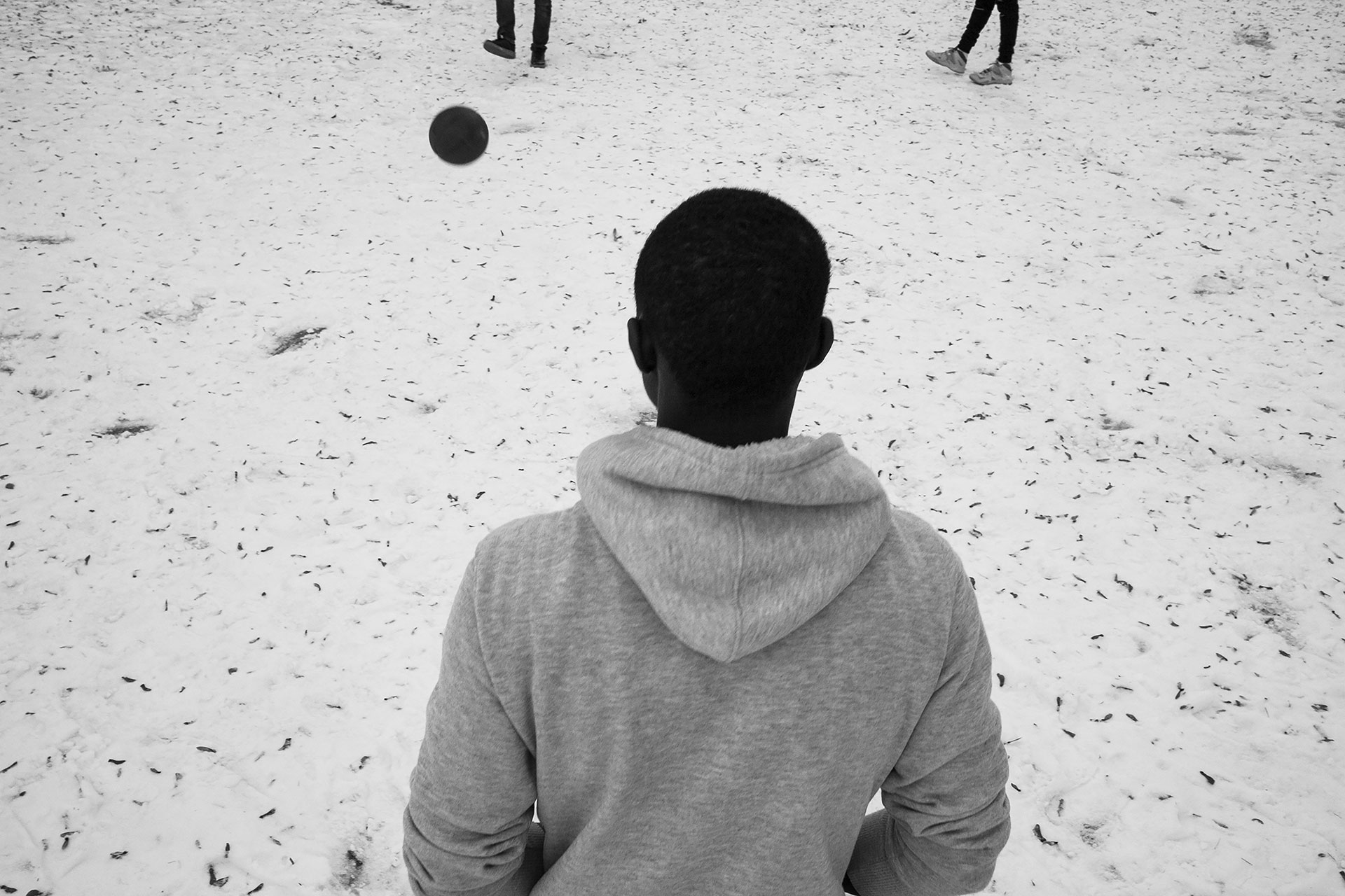 Baba, de Senegal, juega al fútbol con Malick, de Gambia, y Mohammed, de Malí, en un parque cubierto de nieve cercano al centro donde viven. Malick, al igual que otros compañeros, vio la nieve por primera vez durante el invierno de 2017.