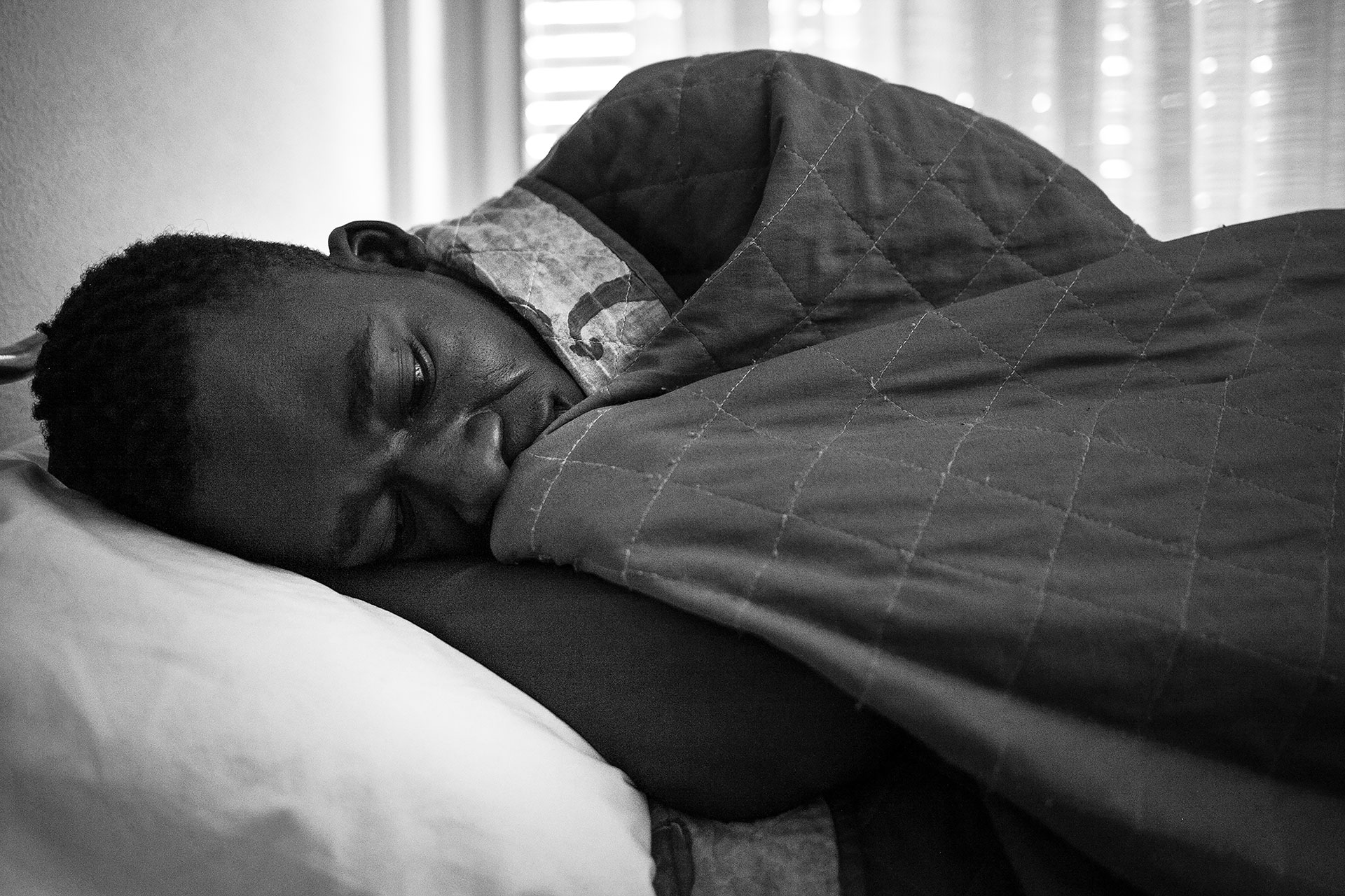 Malick lying in his bed in Hotel Colibri. He shares a room with three other people from The Gambia and Senegal.