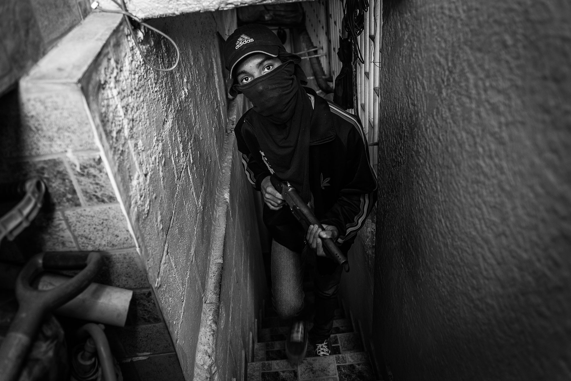 Freddy, aged 16, a member of a kidnapping gang, in a “safe house” in Caracas. He joined the gang when he realised how difficult things were at home. “I saw my mother struggling to buy flour, rice, anything. That is when I decided to join the gang, to be able to buy some food for my little brothers and sisters. I started as a thief but now they have given me a weapon so I can also take part in kidnappings,” he explained.