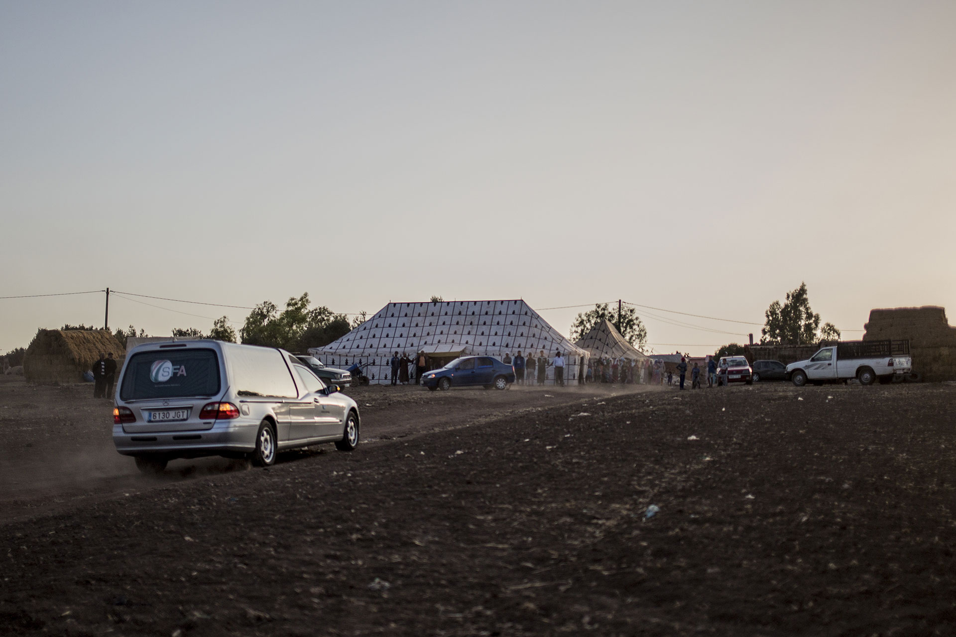 The hearse carrying Zohra Sarrouj’s corpse approaches the family farm where family and friends are waiting.