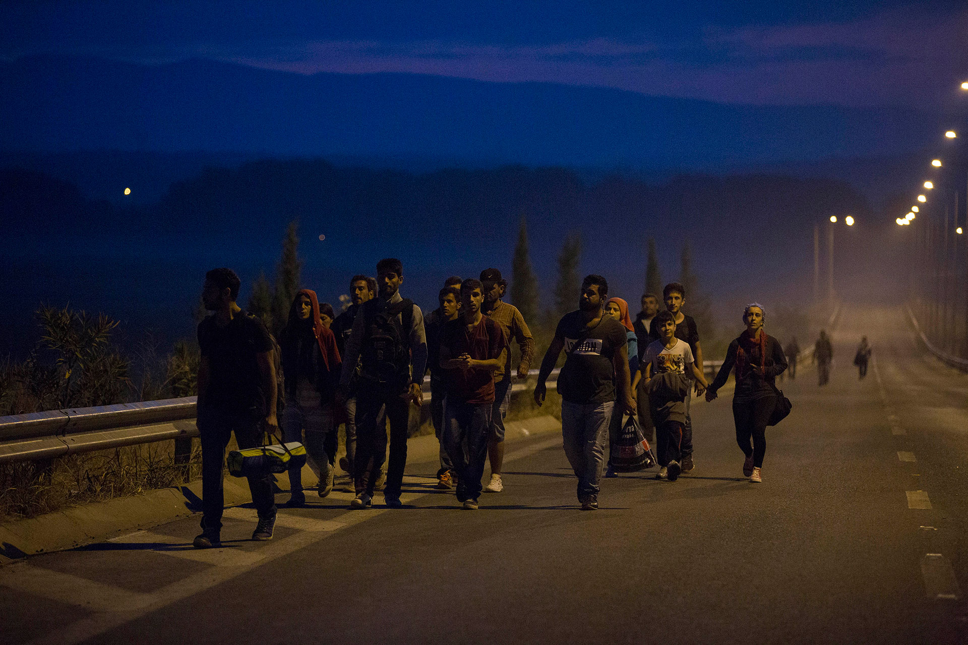 Refugees walk along a road at dawn in Idomeni, Greece, heading towards the border with Macedonia, located a few kilometers away. (Idomeni, Greece. 08/25/2015).