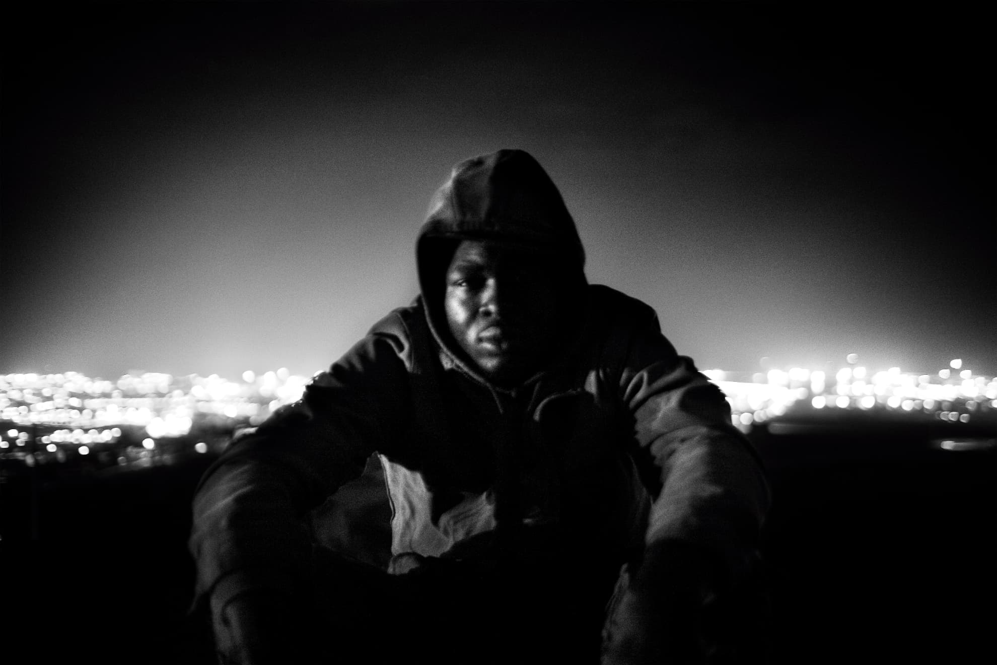 Narcisse, from Cameroon, moments before attempting to jump the fence. In the background, the city lights of Melilla. Narcisse was able to cross over to Melilla that night.