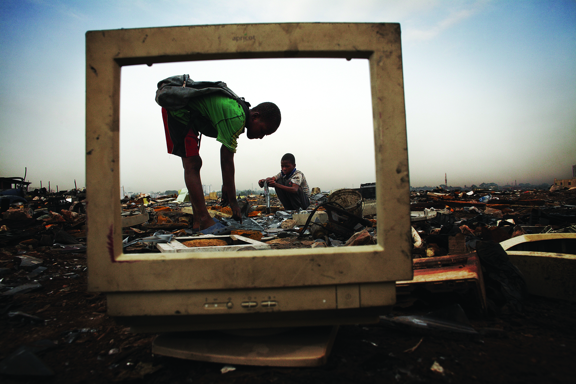 Children break apart CRT monitors to salvage metal from inside, at Agbogbloshie dump. Many children work at the dump salvaging metals which they sell to middlemen. They do not wear any protective clothing and so expose themselves to lethal doses of hazardous chemicals like mercury and lead.