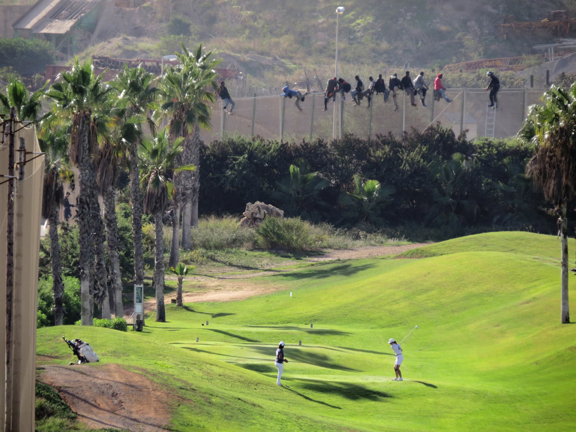 A group of migrants perched on the Melilla fence in front of the golf course in October 2014.