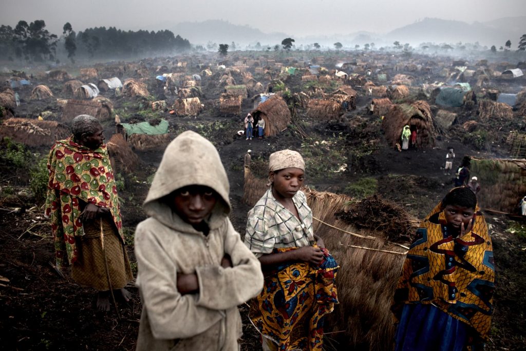 Internally displaced persons stand in the rain in the Chefferie IDP site, home to some 4,000 people, in the town of Kitchanga, North Kivu, DR Congo. The camp started to form in Oct/Nov 2007 and as of Feb 2008 still had not received humanitarian assistance due to the instability of the area.