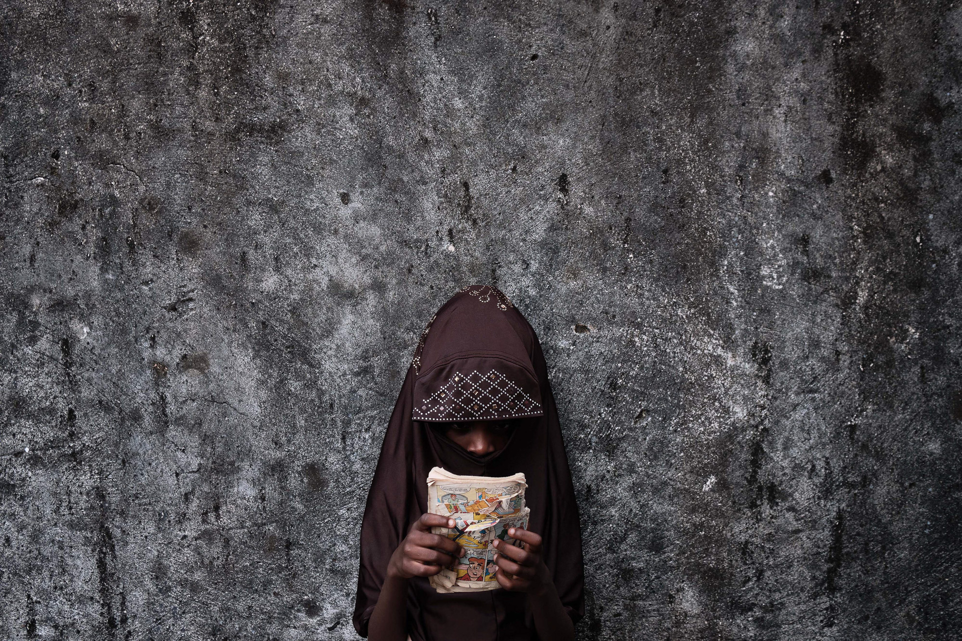 Fatimah is 6 years old, born in Boko Haram captivity to a mother who died during a raid. She spents time at her extended family home in Borno North East Nigeria, scanning pictures of a comic book 'Archie', hoping that one day she will go to school.