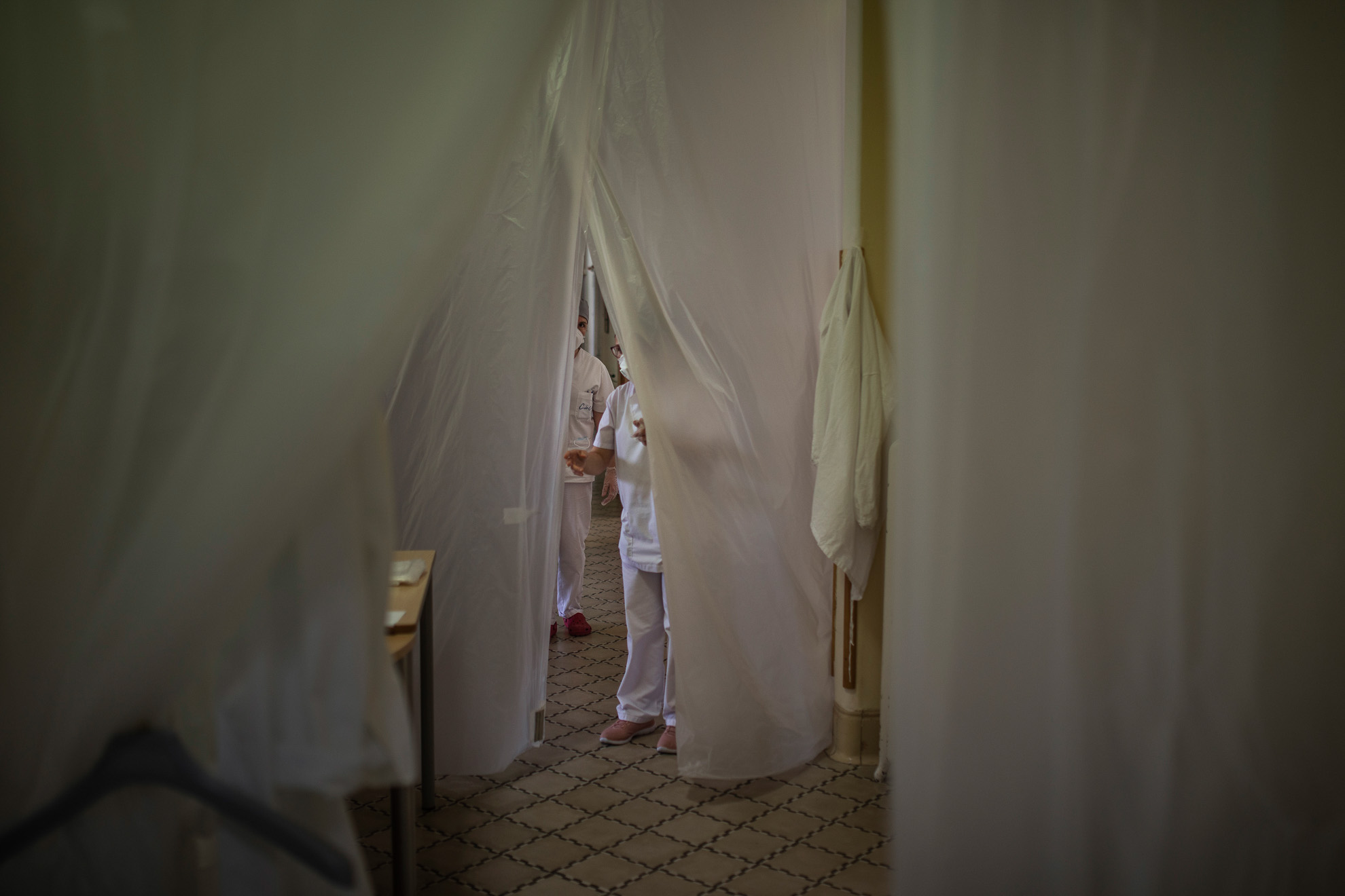 Una enfermera se asoma al interior de una residencia a través de unas cortinas colocadas como protección frente al coronavirus, en la provincia de Barcelona, España, 14 de abril, 2020.