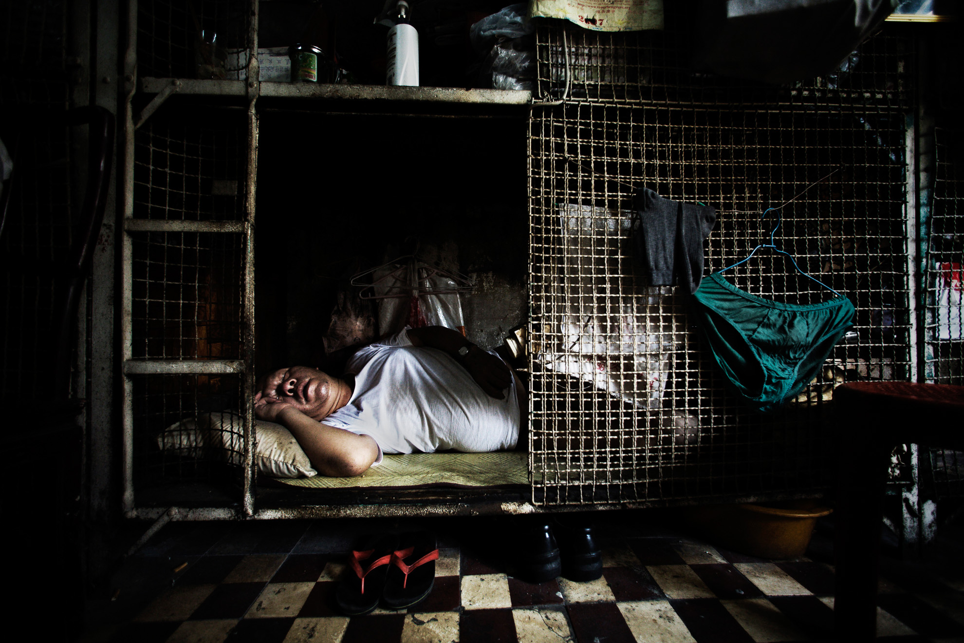 Yan Chi-keung sleeps in his small cage at the Hong Kong's Tai Kok Tsui district, July 16, 2008. In older districts such as Tai Kok Tsui, hundreds of elderly men still reside in caged cubicles in cramped, old tenement flats which house up to 12 individuals in often squalid conditions.