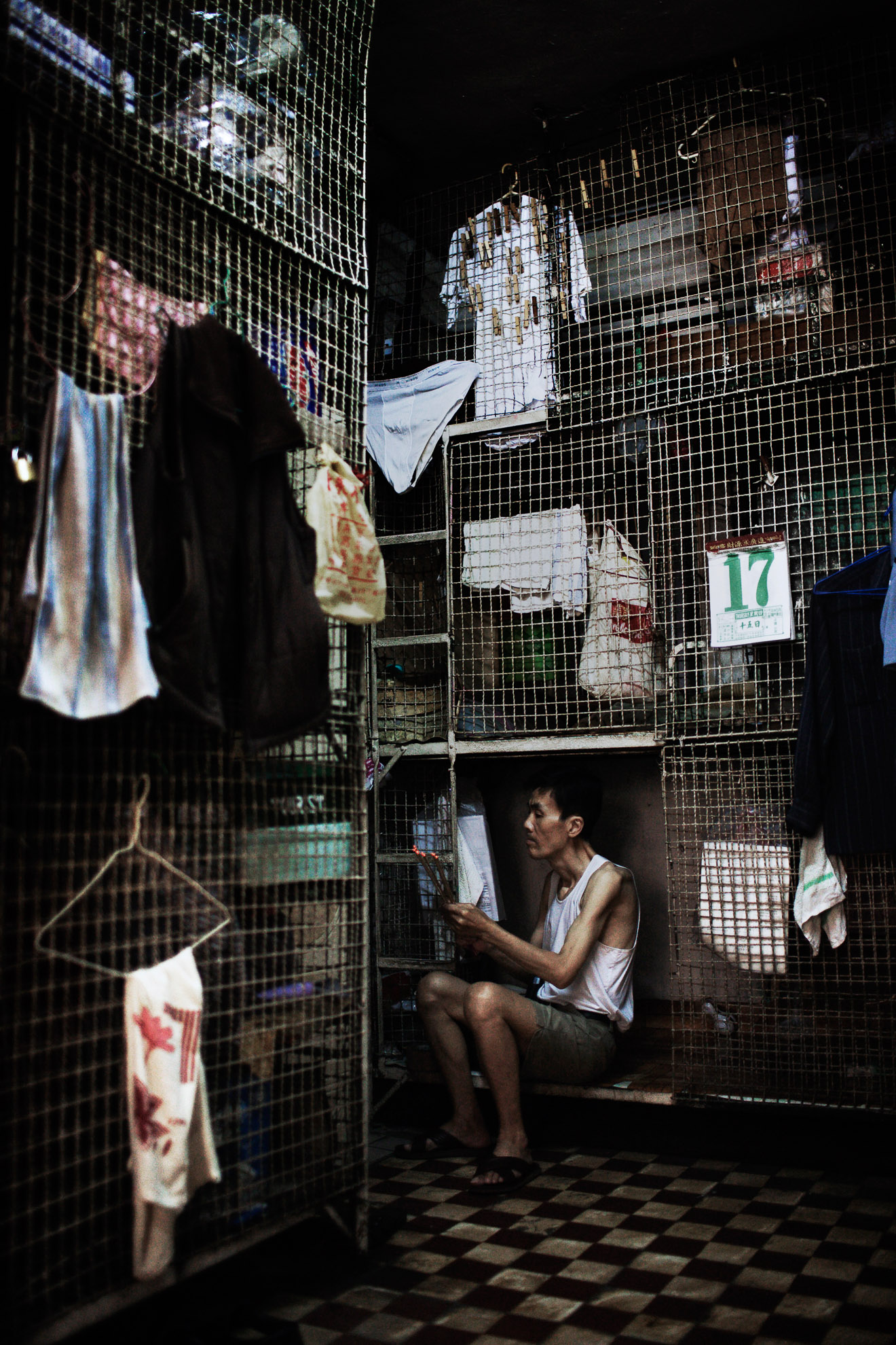 A man burns incense sticks seated in his small cage at the Hong Kong's Tai Kok Tsui district, July 16, 2008. In older districts such as Tai Kok Tsui, hundreds of elderly men still reside in caged cubicles in cramped, old tenement flats which house up to 12 individuals in often squalid conditions.