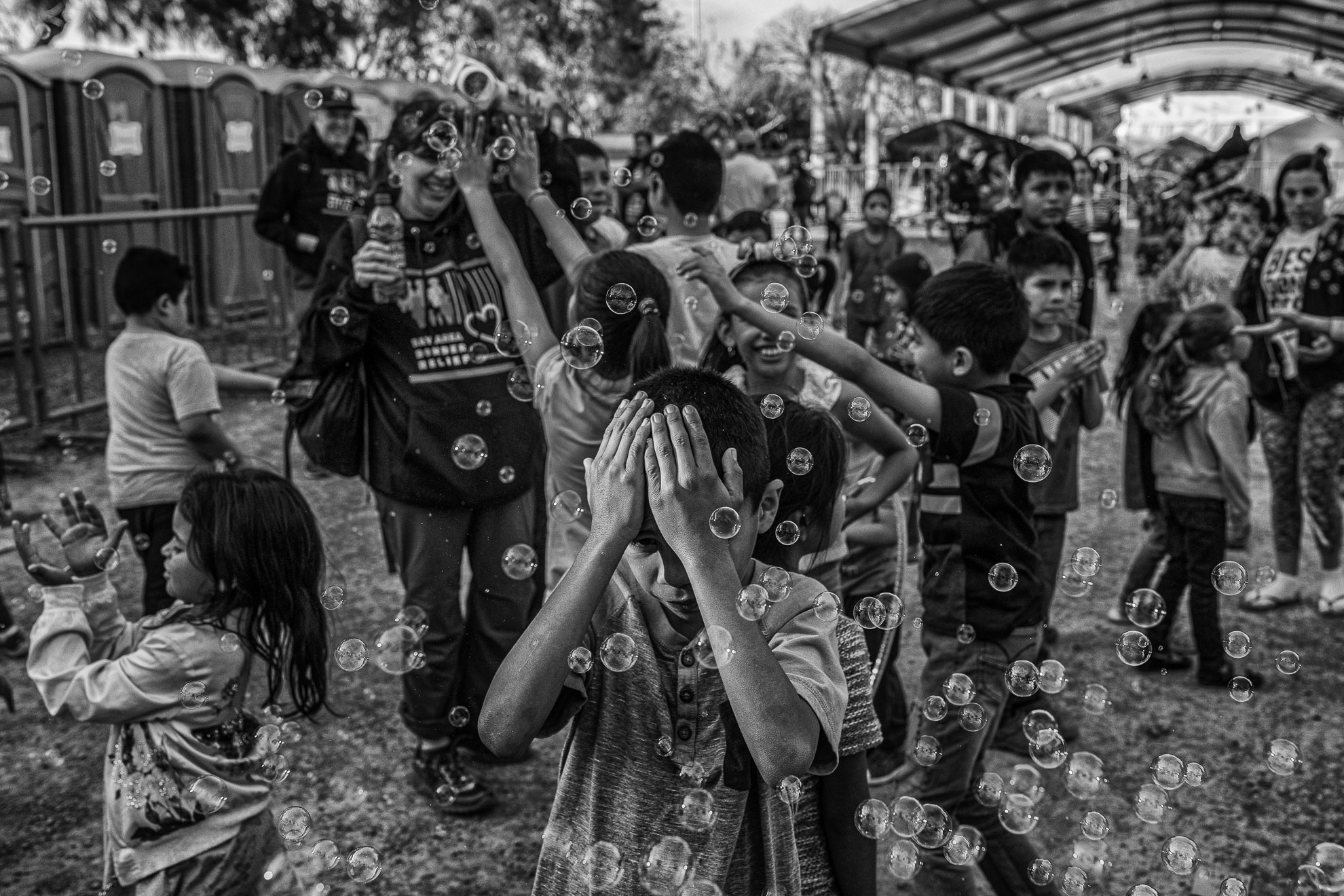 Un niño se cubre la cara de las burbujas en un campamento de solicitantes de asilo en Matamoros.