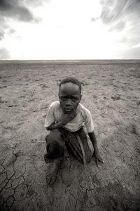 Esta foto representa el hambre y las privaciones en Sudan y la lucha diaria de sus gentes por sobrevivir. La tristeza y la dureza de la foto contrasta con la fuerte luz de fondo que parece gritar: "Ayudad a los niños de Sudan, no los abandonéis, aún hay esperanza!".