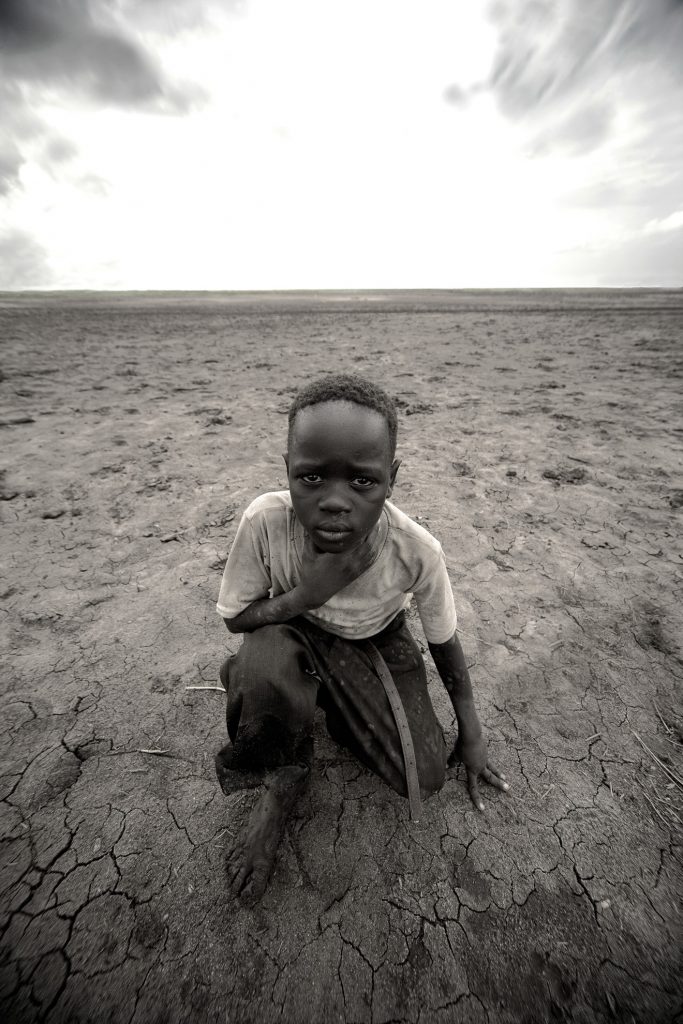 Esta foto representa el hambre y las privaciones en Sudan y la lucha diaria de sus gentes por sobrevivir. La tristeza y la dureza de la foto contrasta con la fuerte luz de fondo que parece gritar: "Ayudad a los niños de Sudan, no los abandonéis, aún hay esperanza!".
