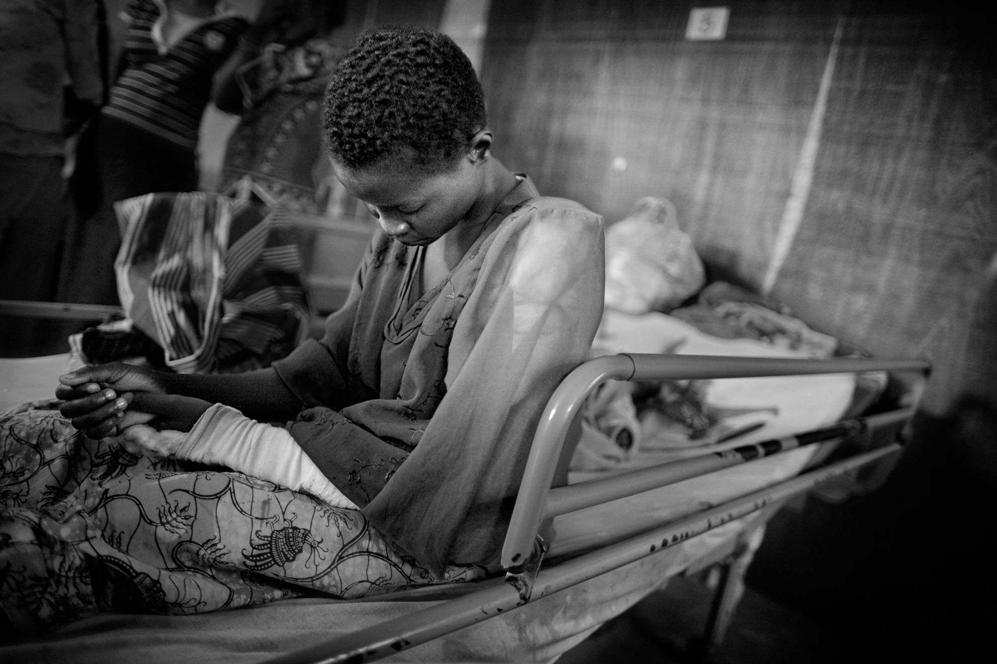 Zawa Antoinette, de 18 años, en el hospital Heal Africa en Goma. “Intenté escapar de los enfrentamientos en mi pueblo, pero quedé atrapada en el fuego cruzado. Me dispararon en el brazo”. Zawa tuvo que andar desde su pueblo hasta el hospital con su único hijo en brazos. El campo estaba abarrotado y las personas recién llegadas vivían en hangares de plástico y dormían en suelo sucio. Otras muchas se refugiaron en iglesias, escuelas y domicilios privados cerca de Goma. En el centro de recepción pude hablar con Kaboyeneye Sibomana, de 28 años. Llevaba dos días allí, a la espera de un lugar donde poder vivir, con sus hijos en el regazo. “Anduvimos durante tres días antes de llegar al campamento. En mi ciudad todo el mundo huyó: unas 5.000 personas. Ahora tenemos que ser pacientes y esperar que la guerra termine pronto”.