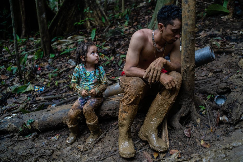 Luis Miguel Arias, venezolano de 27 años, descansa exhausto junto a su hija Melissa Arias de 4 años durante el segundo día de caminata cruzando el Tapón del Darién entre Colombia y Panamá. El cruce de la selva puede tomar entre 10 y 12 días. Septiembre de 2022.