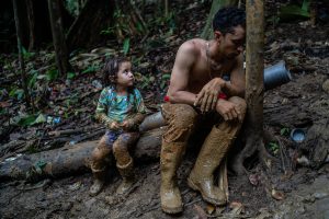 Luis Miguel Arias, venezolano de 27 años, descansa exhausto junto a su hija Melissa Arias de 4 años durante el segundo día de caminata cruzando el Tapón del Darién entre Colombia y Panamá. El cruce de la selva puede tomar entre 10 y 12 días. Septiembre de 2022.