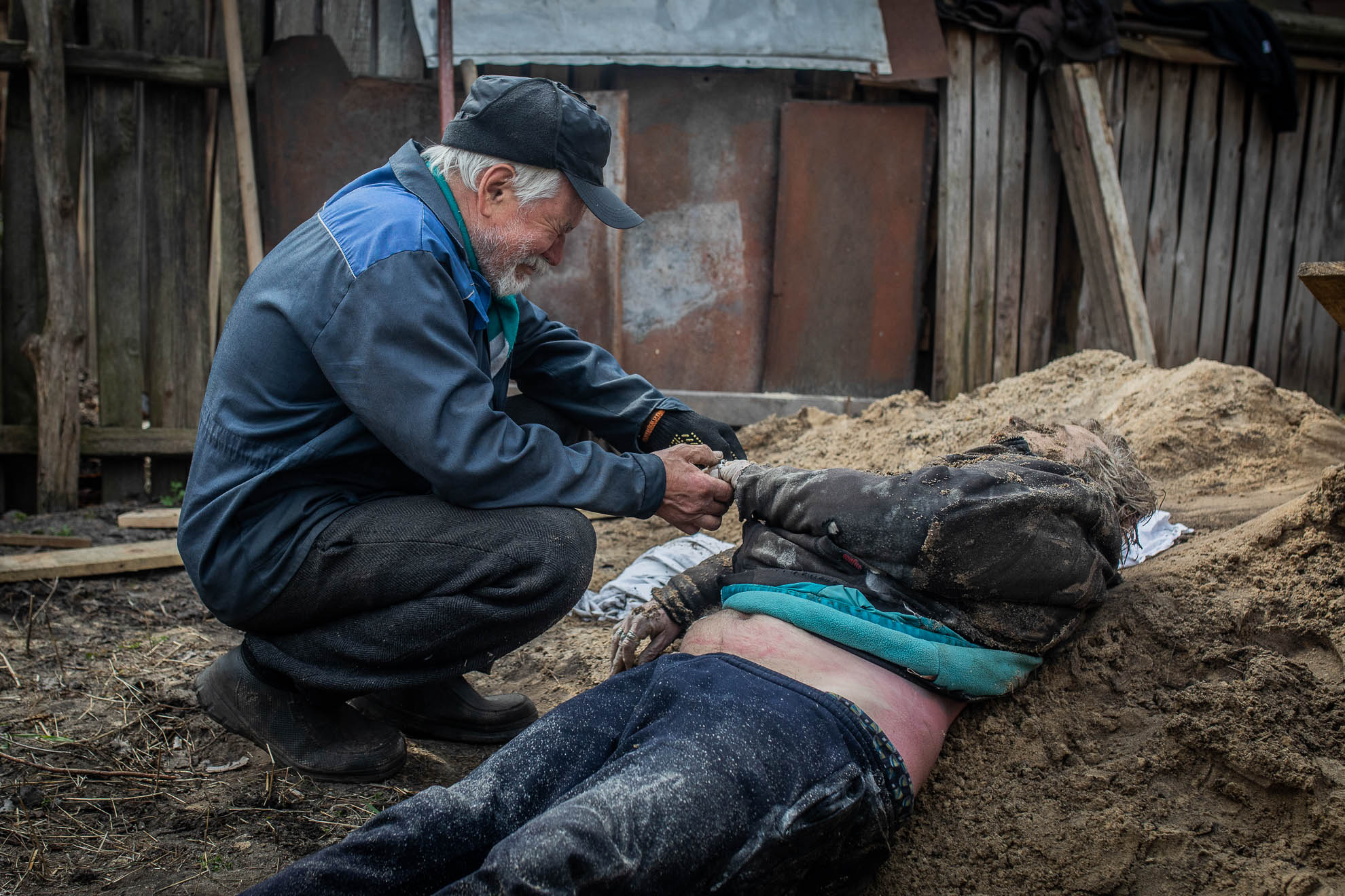 Valeriy cries next to the body of his eldest son, Oleksiy, shot dead in the center of Bucha on March 12. His body, which had been temporarily buried in the garden of his home, was dug up on April 8 to be transferred to a morgue for an autopsy before being cremated. The disinterment was attended by Valeriy himself along with his other son, Andriy, and family, friends, and police officers.