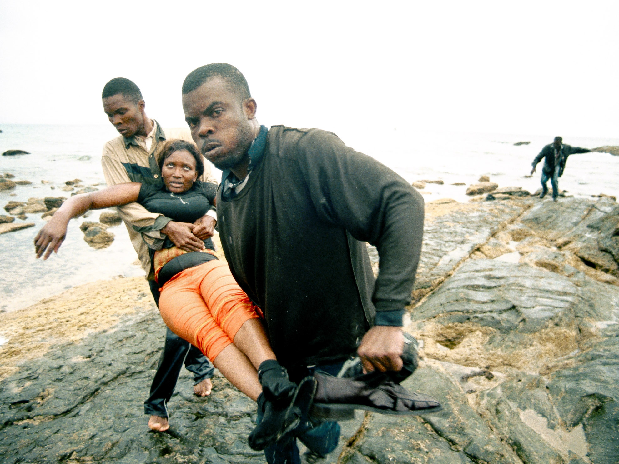 Dos inmigrantes subsaharianos sacan a una compañera que está embarazada del agua en las playas de Tarifa.