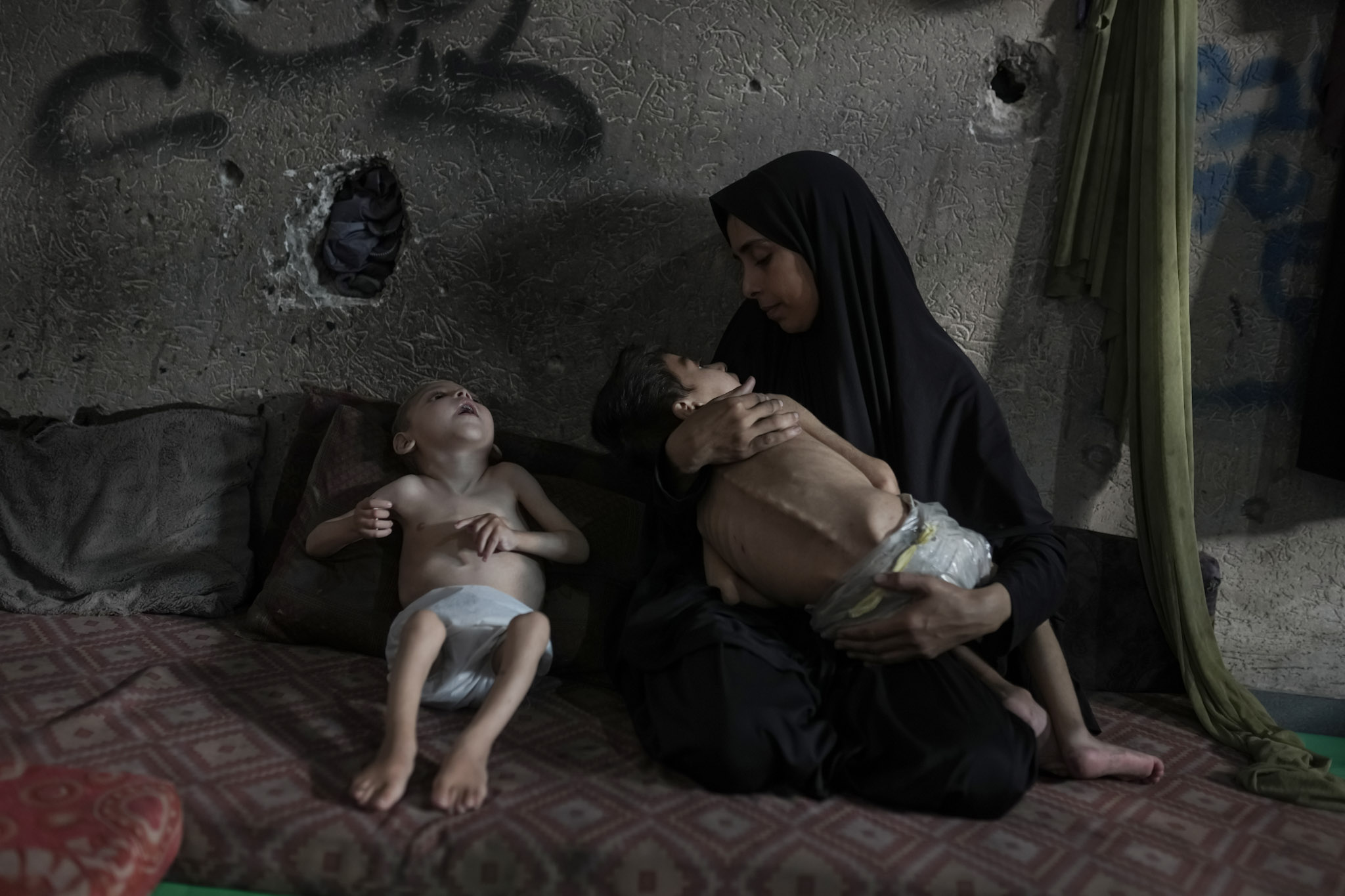 Samah Matar posa para una foto con sus hijos Yousef, de 6 años, en brazos, y Amir, de 4, que padecen desnutrición y parálisis cerebral, en una escuela gestionada por la Naciones Unidas en la ciudad de Gaza, el sábado 26 de julio de 2025. En Gaza, la desnutrición suele agravarse por condiciones preexistentes y por enfermedades relacionadas con la atención sanitaria inadecuada y el saneamiento deficiente, en gran parte como resultado de la guerra.