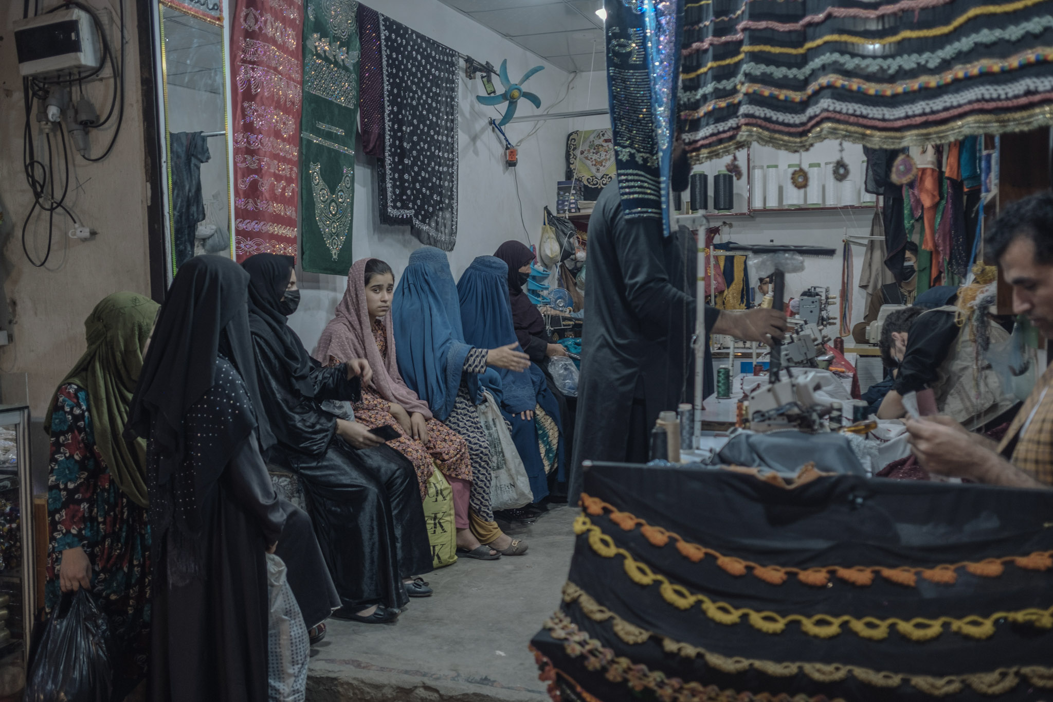 Un grupo de mujeres espera en una sastrería a que terminen sus prendas. La policía local de moralidad talibán ha ordenado a los sastres varones dejar de confeccionar vestidos para mujeres y niñas. Si bien no se ha emitido una prohibición total, sí se les ha prohibido tomar medidas directamente a mujeres. Incumplir esta orden puede llevar al cierre del negocio.