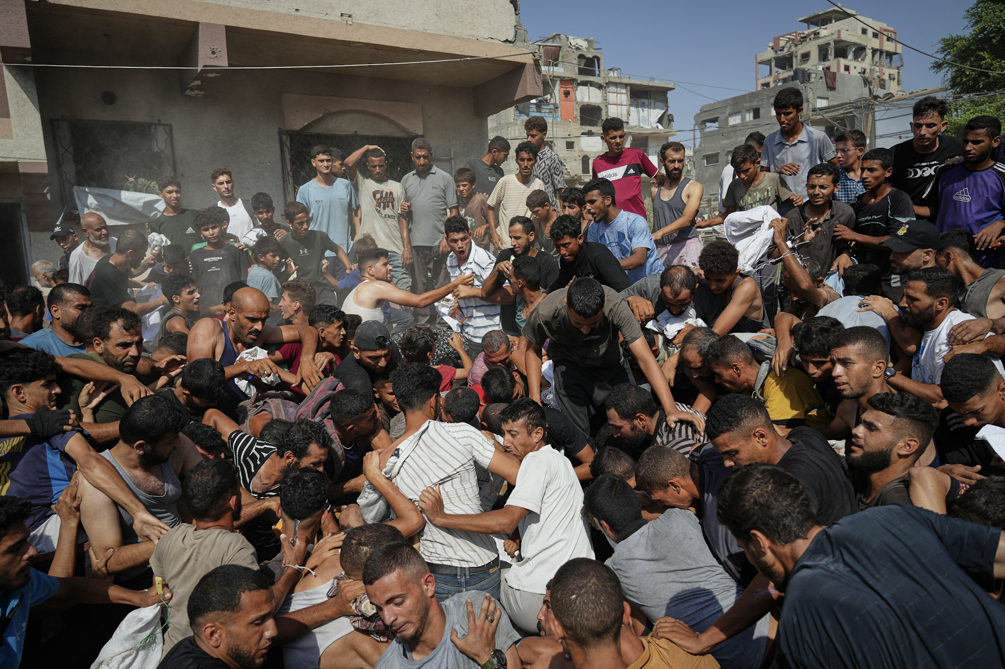 Palestinos luchan por recoger la ayuda humanitaria lanzada en paracaídas sobre la ciudad de Gaza, en el norte de la Franja de Gaza, el jueves 14 de agosto de 2025.