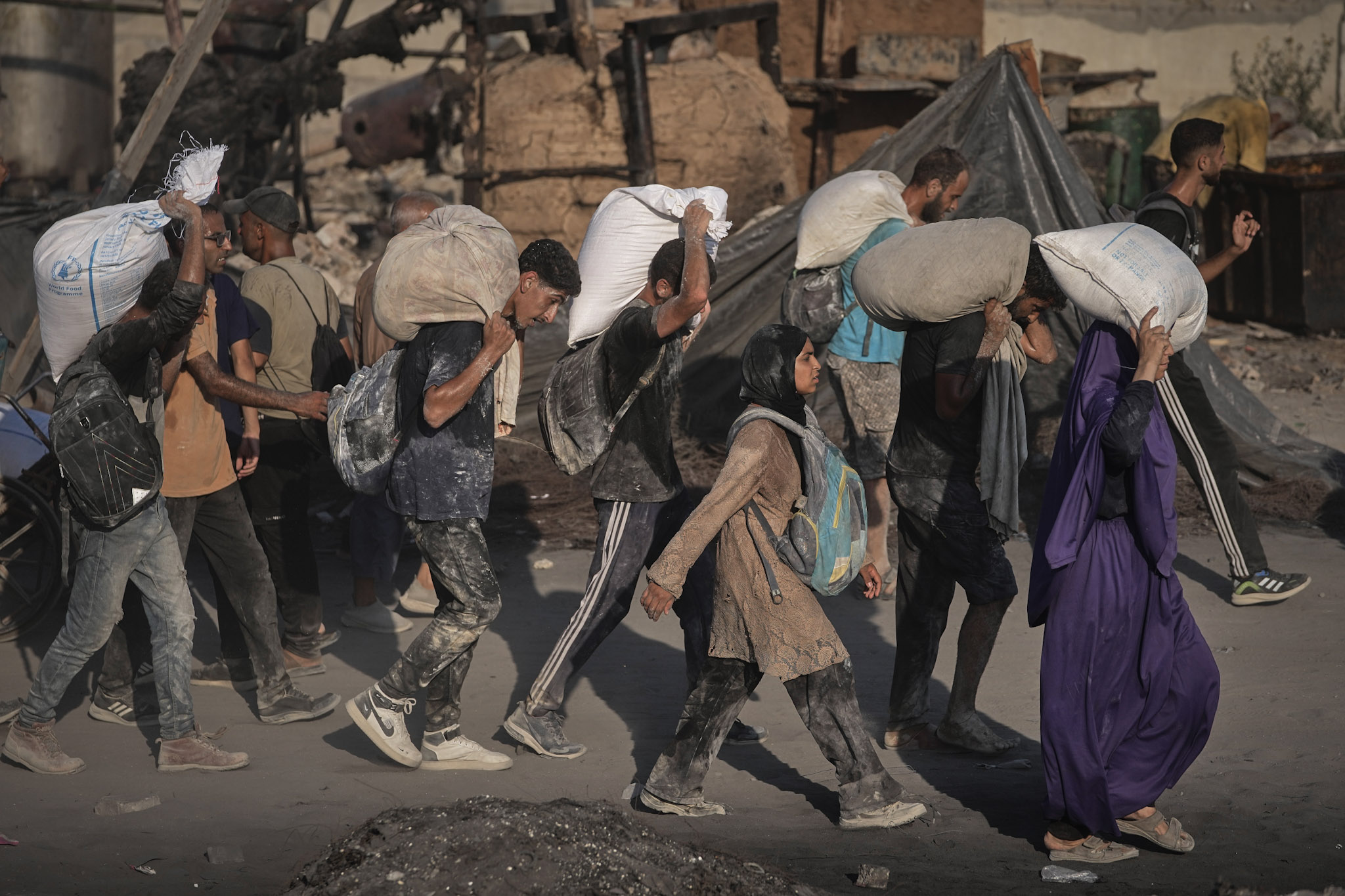 Palestinos transportan sacos de harina descargados de un convoy de ayuda humanitaria que llegó a la ciudad de Gaza desde el norte de la Franja de Gaza, el sábado 26 de julio de 2025.