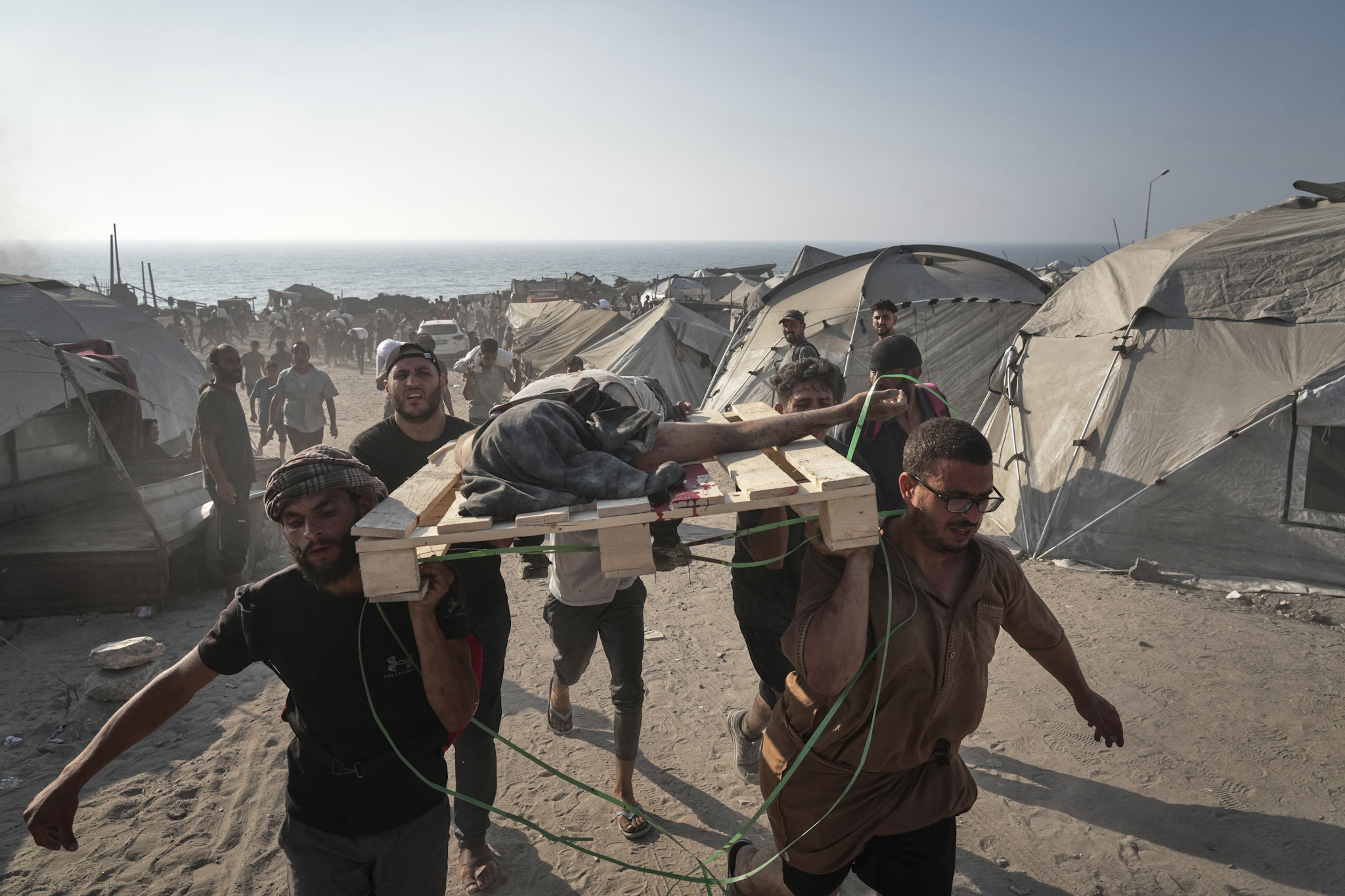 Palestinos transportan el cadáver de un hombre que murió al intentar alcanzar los camiones de ayuda humanitaria que entraron en la ciudad de Gaza desde el norte de la Franja de Gaza, el sábado 26 de julio de 2025.