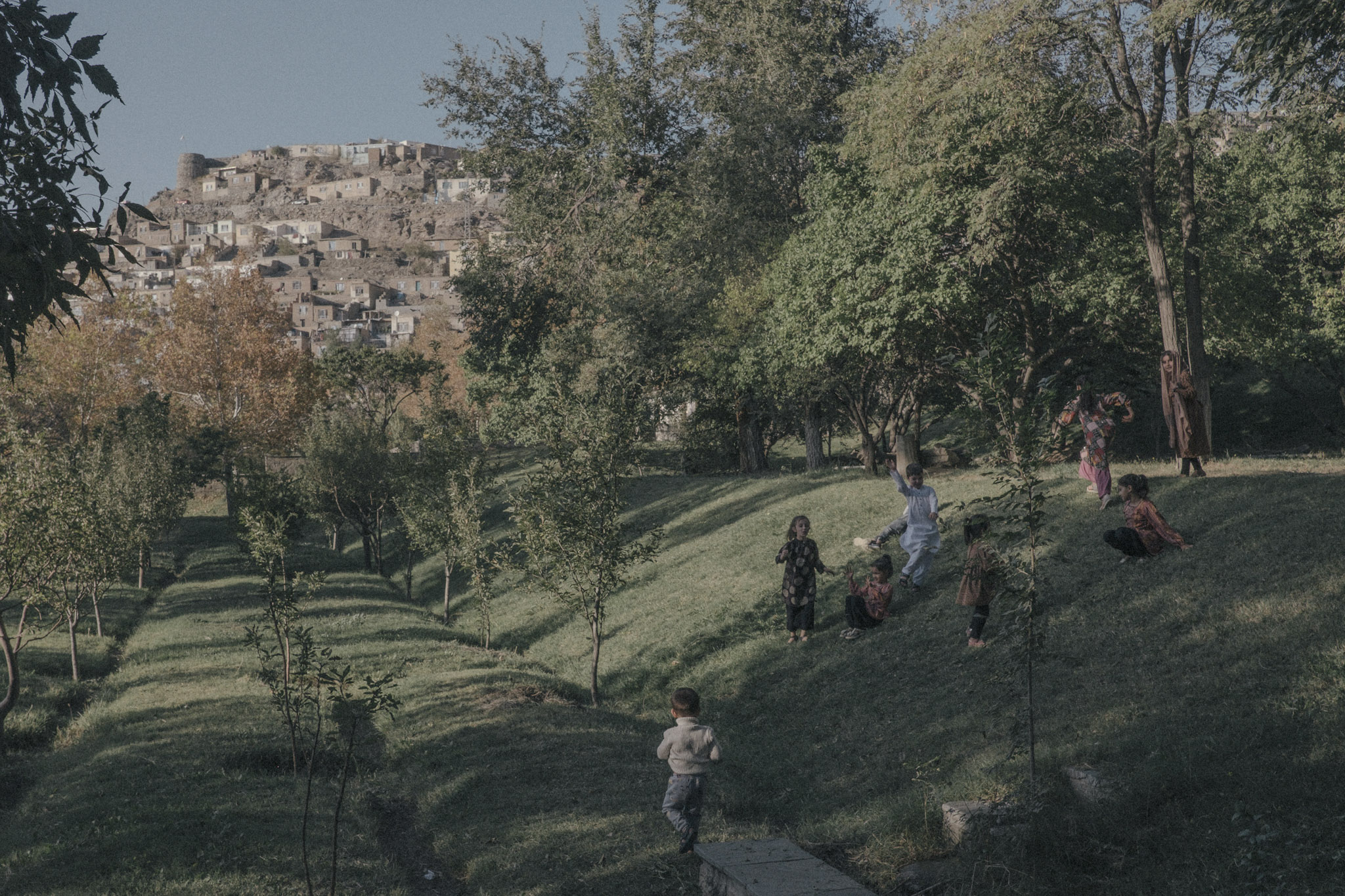 Niños juegan en el Jardín de Babur, un parque icónico de más de mil metros cuadrados en Kabul. Desde el regreso de los talibanes, las mujeres tienen prohibido ingresar a los jardines públicos, lo que ha eliminado una de las funciones esenciales del Jardín de Babur como espacio social para toda la población. Los hombres pueden llevar a sus hijos, y las niñas pequeñas pueden entrar solo mientras son muy jóvenes.