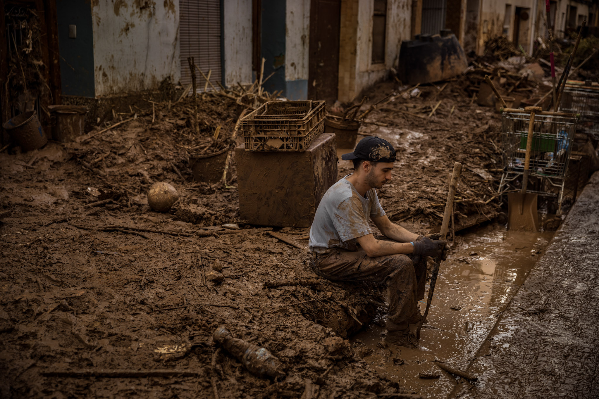 Pablo Mendoza, un estudiante de biología de 21 años de Cádiz (sur de España) que estudia en Valencia, descansa sobre el barro en la calle Sant Josep, una de las zonas más afectadas, al final de una jornada limpiando las calles de Paiporta. En ese momento Pablo llevaba seis días consecutivos ayudando, como voluntario, a retirar el barro acumulado en las calles y casas de Paiporta, devastadas por las inundaciones del 29 de octubre.
