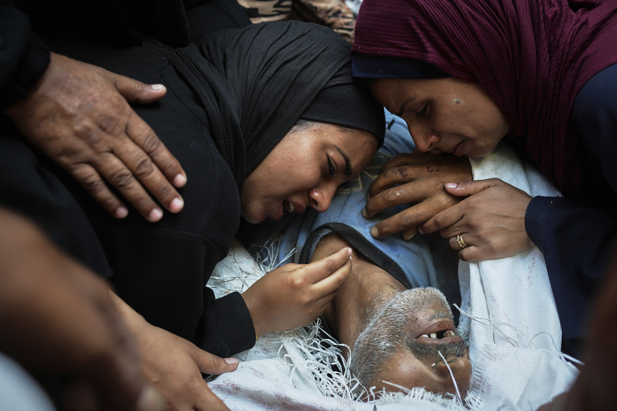 En el hospital Shifa de la ciudad de Gaza, un grupo de mujeres llora junto al cadáver de su padre, Abd Rahman Al-Baba, que murió por intentar alcanzar los camiones de ayuda que entraban en el norte de la Franja de Gaza a través del paso fronterizo de Zikim con Israel. Lunes, 4 de agosto de 2025.
